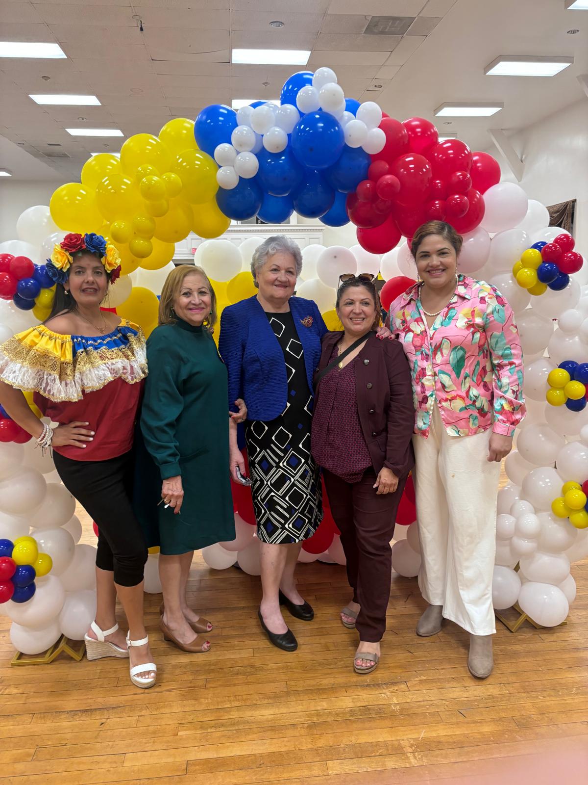 Community members posing under a Venezuelan flag balloon arch